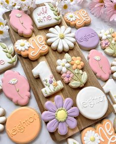 some decorated cookies are on a wooden board with daisies and daisies in the background