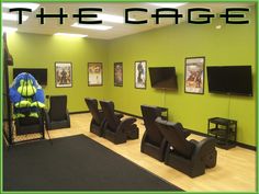 an office with chairs and televisions in the corner, green walls and black carpet