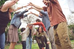 a group of people standing around each other with their arms in the air and one person holding out his hand