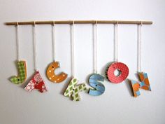 the letters are made from different types of fabric and hang on a wooden rod in front of a white wall