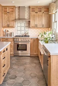 a kitchen with wooden cabinets and stainless steel stove top oven in the center, surrounded by hexagonal tile flooring