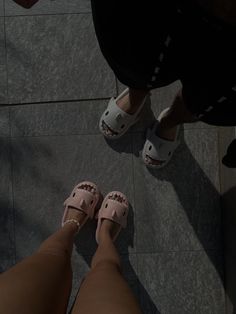 two people standing next to each other wearing pink shoes and white slippers on their feet