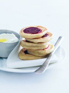 pancakes with jam and butter on a plate next to a bowl of yogurt