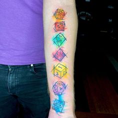 a person with a tattoo on their arm that has different colored dices in it