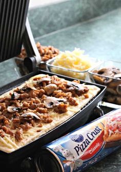 an assortment of food items including pizza, pasta and cheeses on a counter top