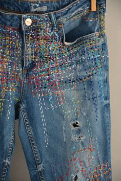 a pair of blue jeans with colorful stitchs on them