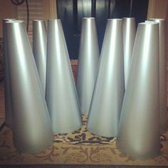 four silver vases sitting on top of a rug in front of a black door