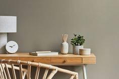 a wooden table topped with a lamp next to a white vase filled with green plants