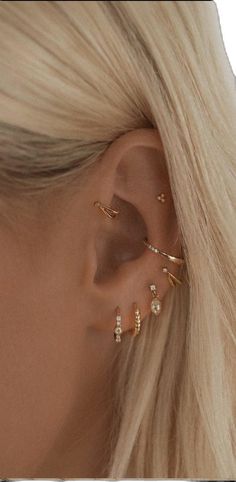 a woman with blonde hair wearing three different ear piercings on her left side and one behind the ear