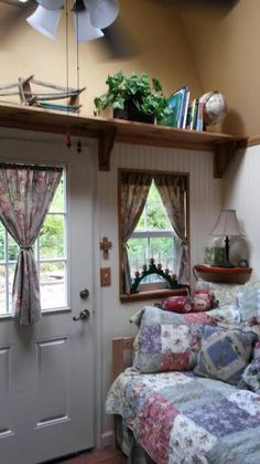 a room with a bed, window and fan on top of the door sill