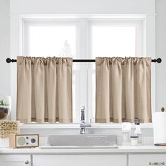 a kitchen window with two curtains and a sink