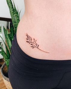 a woman's stomach with a small flower tattoo on the side of her belly