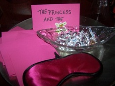 a glass bowl filled with candy next to a pink sign and envelopes on a table