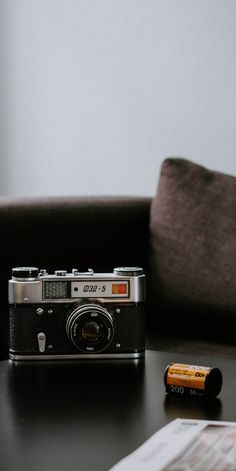 an old camera sitting on top of a table next to a pen and paper towel