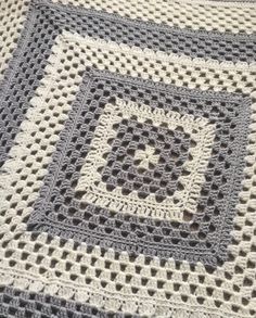 a crocheted blanket that is on top of a tablecloth with a black and white design