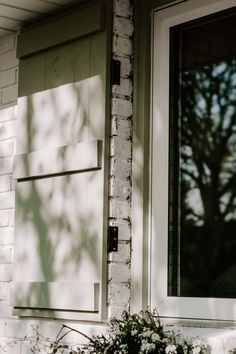 a cat is sitting on the ledge of a window sill next to a potted plant