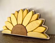 a wooden sunflower decoration sitting on top of a wood table next to a white wall