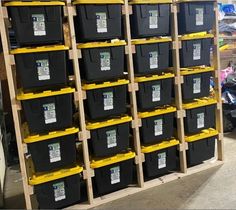 several black and yellow bins are stacked on pallets in a storage room with other items