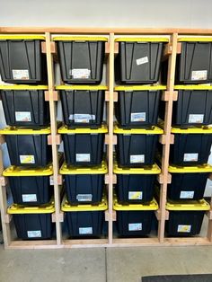 several bins are stacked on wooden shelves in a storage room with yellow and black containers