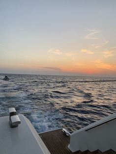 the sun is setting over the ocean as seen from a boat on the water in the distance