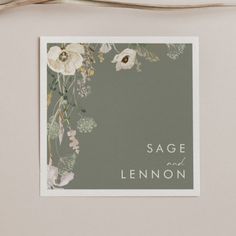 the sage and lemon wedding stationery is displayed in front of a gray background with white flowers