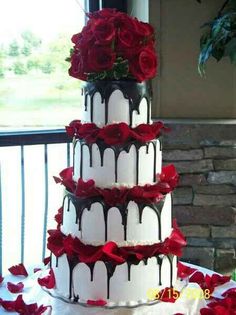 a three tiered wedding cake with red roses on the bottom and white icing