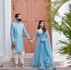 a man and woman standing on steps holding hands