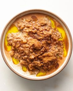 a bowl filled with food sitting on top of a white table next to a spoon