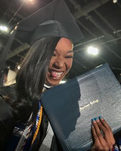 a woman in graduation cap and gown holding a book