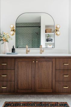 a bathroom vanity with a large mirror above it and a rug on the floor next to it