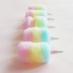 several rainbow colored cotton candy sticks lined up on a white surface with pastel colors