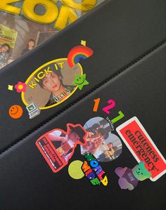 two pieces of black luggage with stickers on them next to various movies and magazines