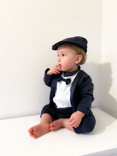 This formal looking 1pc all-in-one long sleeve tuxedo suit with two color option, navy and black. The suit has been designed in a smart, simple way for baby boy. It connects the pure cotton shirt, blazer and trouser into one piece suit, with matching bow tie. The matching color flat cap complete this cute looking and comfort wearing outfit. It offers the little hero a proper formal suit looking with this 1pc practical design. The finest selected fabric ensure a super comfort when wearing. Our mo All In One Outfit, Suit With Hat, Sketching Reference, Wedding Motif, Formal Wedding Suit, Purple Flower Girl Dress, Boys Tuxedo