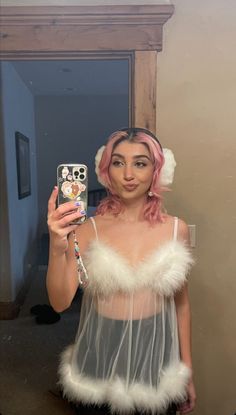 a woman with pink hair taking a selfie in front of a mirror wearing a costume