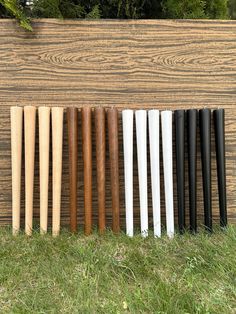 a row of baseball bats sitting on top of a field next to a wooden wall