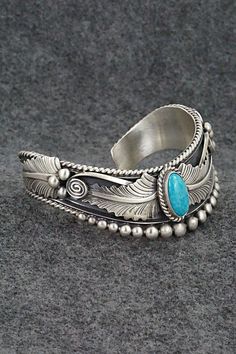 This beautiful turquoise and brushed-finish sterling silver bracelet featuring feathers was made by Navajo silversmith Tom Lewis. The back is signed R.B. and .925.Size: 5 1/2" (will fit up to a 6 5/8" wrist)Gap: 1 1/8"Width: 7/8"Free shipping on all orders! We ship with USPS and always include tracking. All orders ship within a day of payment.Returns are accepted up to 30 days after you receive your order. Just send us a message. Our shop offers cash back or store credit. The item must be returned in new condition. Southwestern Oxidized Adjustable Jewelry, Southwestern Oxidized Bracelet, Elegant Engraved Turquoise Sterling Silver Bracelet, Elegant Turquoise Engraved Sterling Silver Bracelet, Western Style Silver Bracelet Jewelry, Etched Turquoise Sterling Silver Jewelry, Western Style Silver Bracelet, Western Style Sterling Silver Bangle, Southwestern Etched Turquoise Jewelry