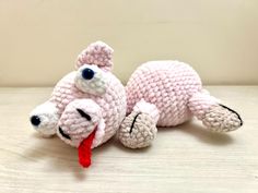 a crocheted stuffed animal laying on the ground with its tongue out and eyes wide open