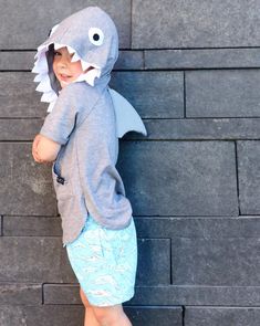 a little boy in a shark costume standing on some steps with his hands behind his head