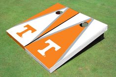 an orange and white cornhole board on the grass with two holes in each side