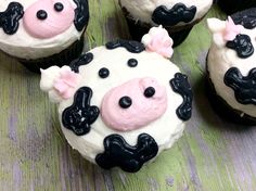 four cupcakes decorated with black and white frosting are sitting on a table