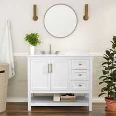 a white bathroom vanity with mirror and potted plant on the floor next to it