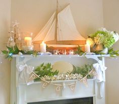 a white mantle with candles and flowers on it in front of a sailboat decorated for christmas