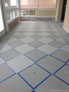 an empty room with blue tape on the floor and windows in the background, all painted white