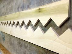 a wooden wall hanging on the side of a building with mountains cut out of it