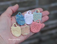 small crocheted purses are in the palm of someone's left hand