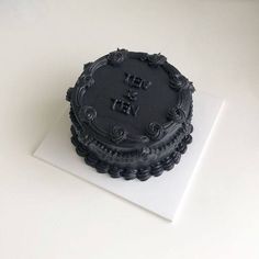 a black cake sitting on top of a white table next to a piece of paper