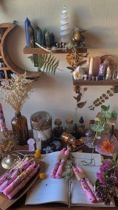 an open book sitting on top of a wooden table next to flowers and candles in vases