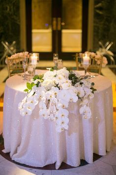 a table with white flowers and candles on it