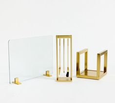 three pieces of brass and glass on a white surface with one piece missing from the mirror