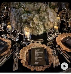 the table is set with silver and gold place settings, black napkins, and white flowers